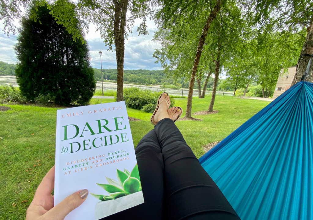 woman in a hammock holding the book called Dare to Decide