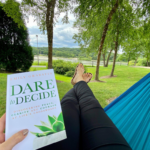 woman in a hammock holding the book called Dare to Decide